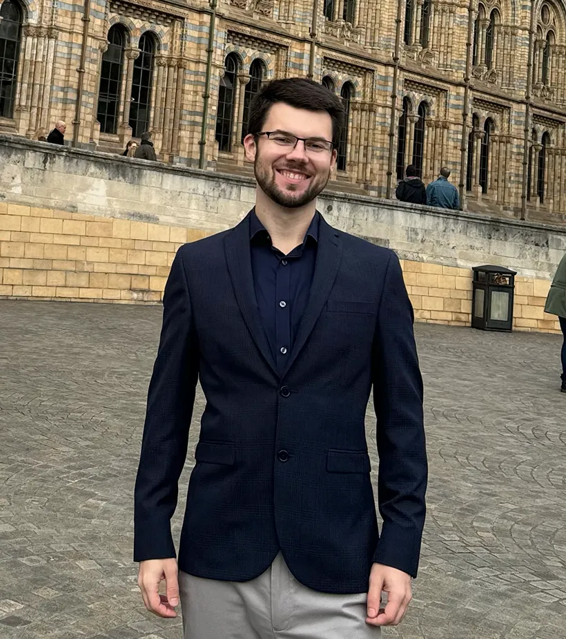 Michal Kups smiling in front of the Natural History Museum in London